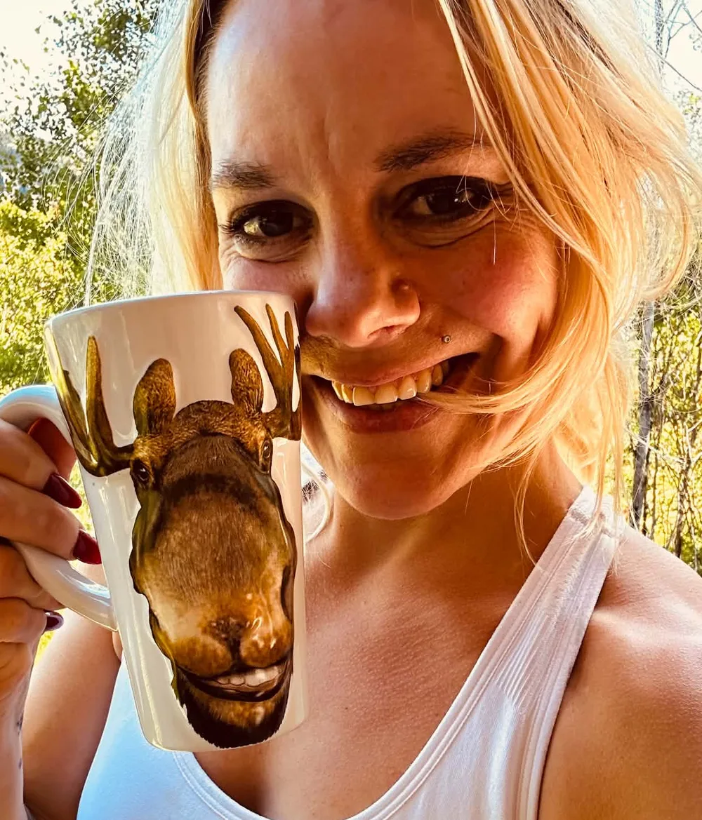 Jillian, your host, smiling on the deck with a moose-shaped mug